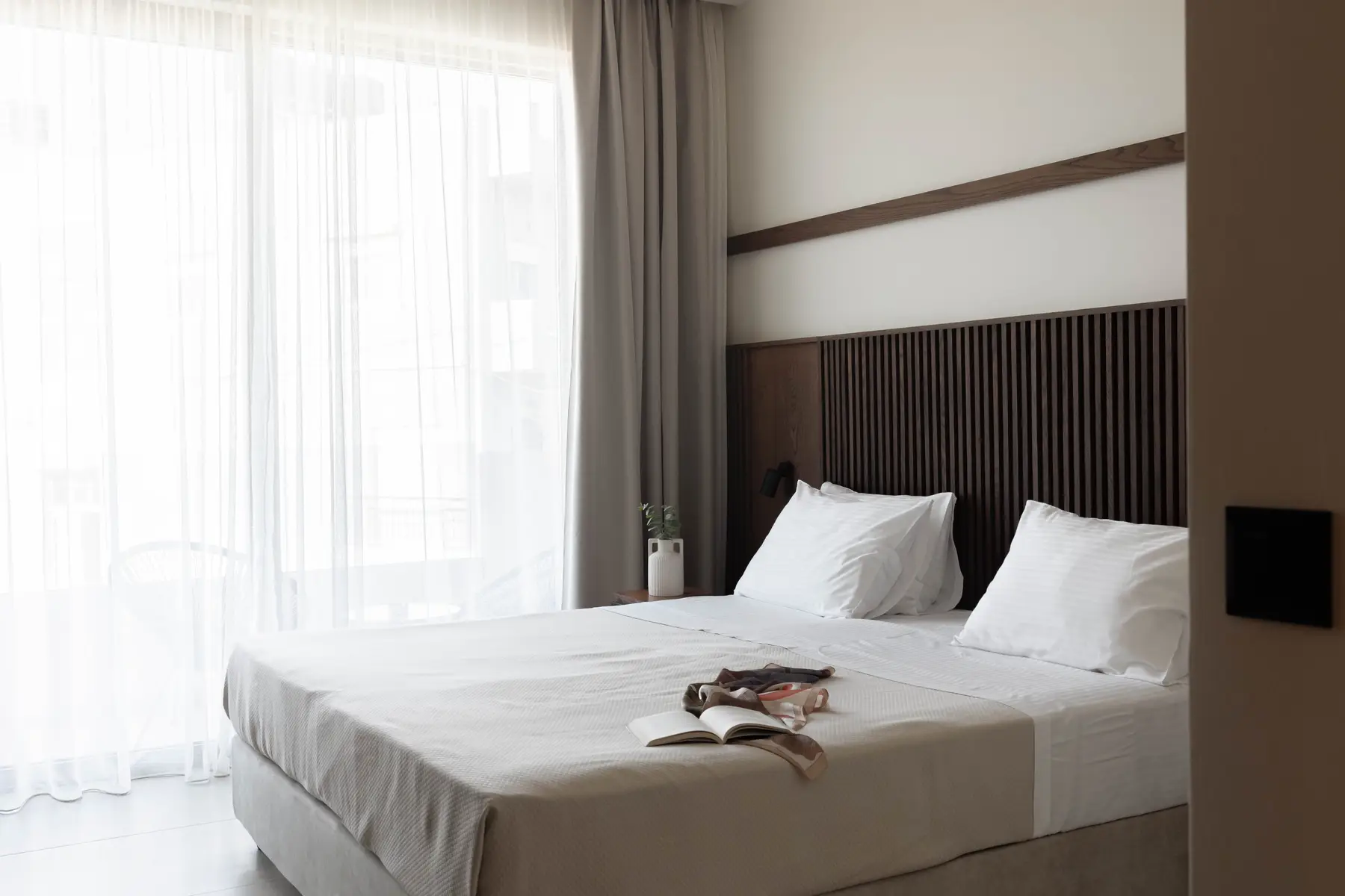 Superior Suite bedroom with slatted oak headboard and soft grey curtains