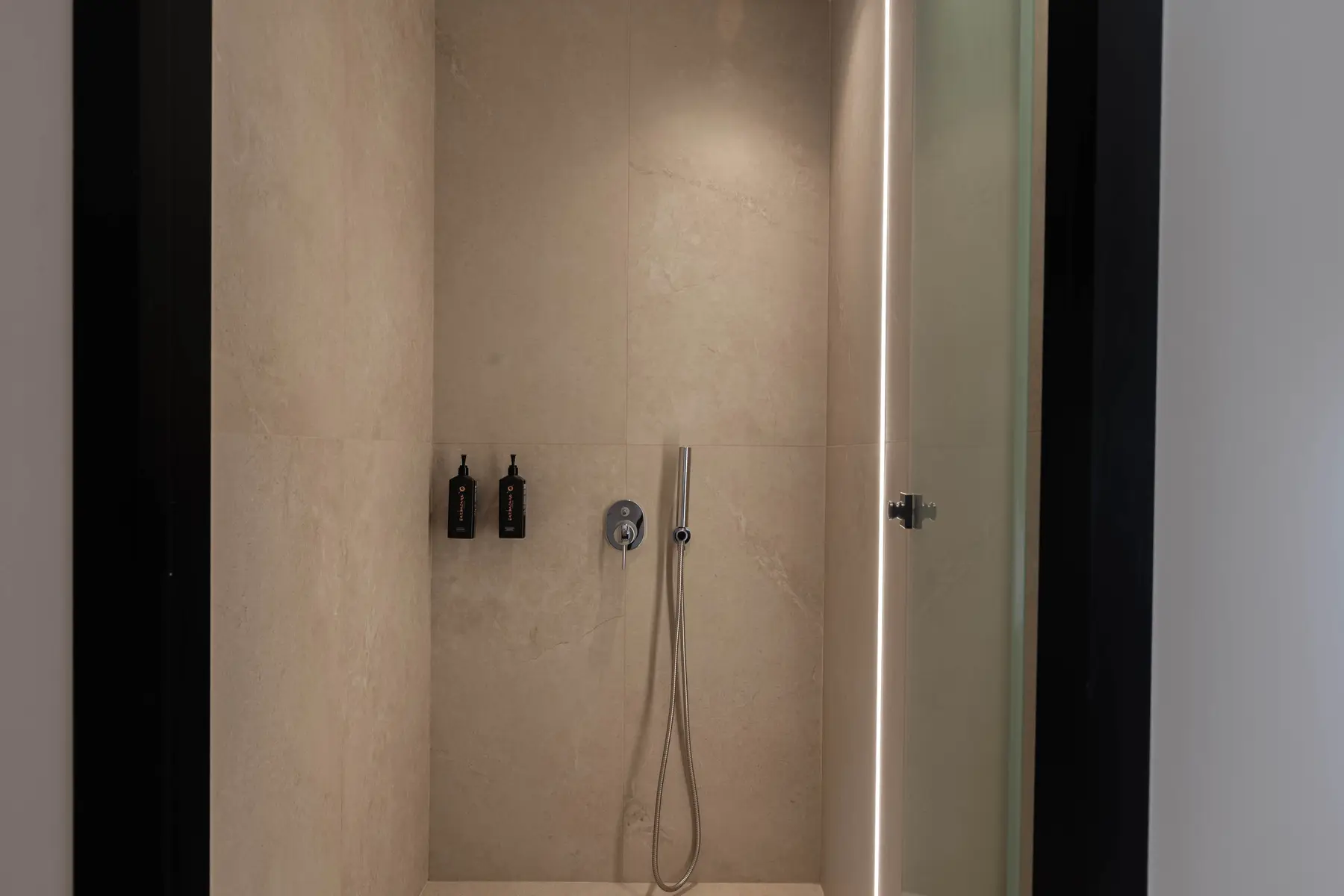 Walk-in rain shower in warm stone tiling