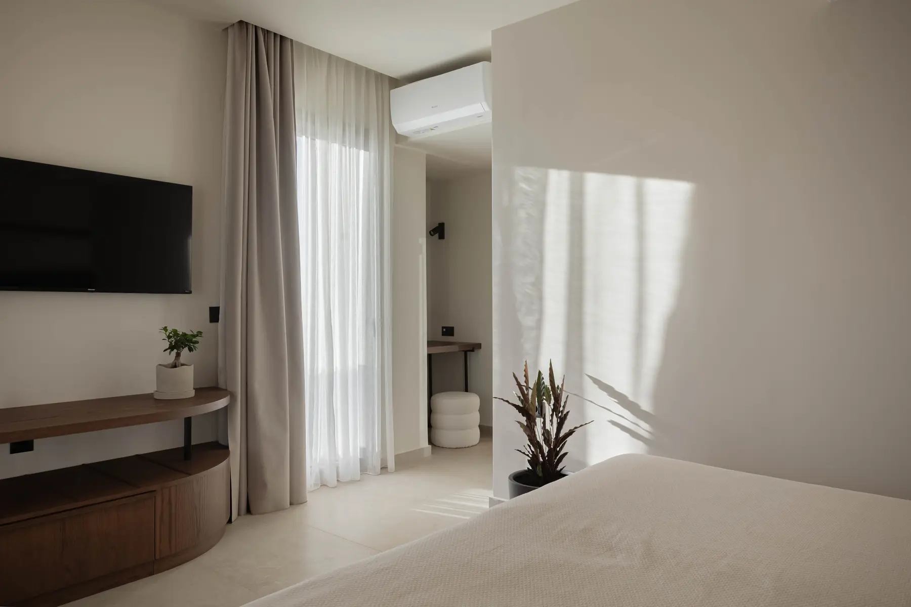 Bedroom with wall-mounted TV and soft drapes