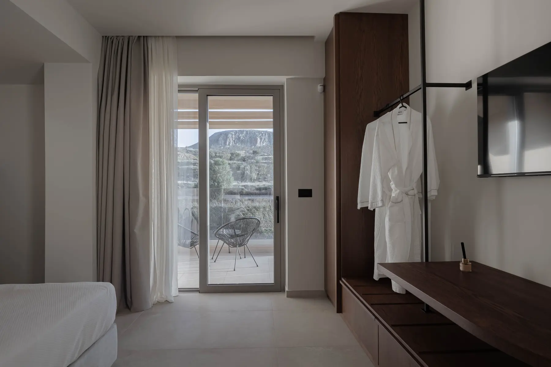 Deluxe bedroom with bathrobe and balcony view of the hillside