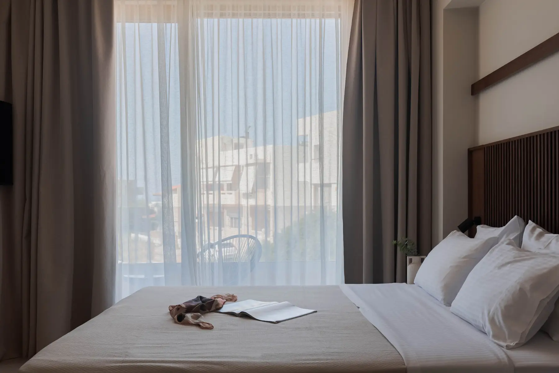 Bedroom opening to the balcony through sheer curtains