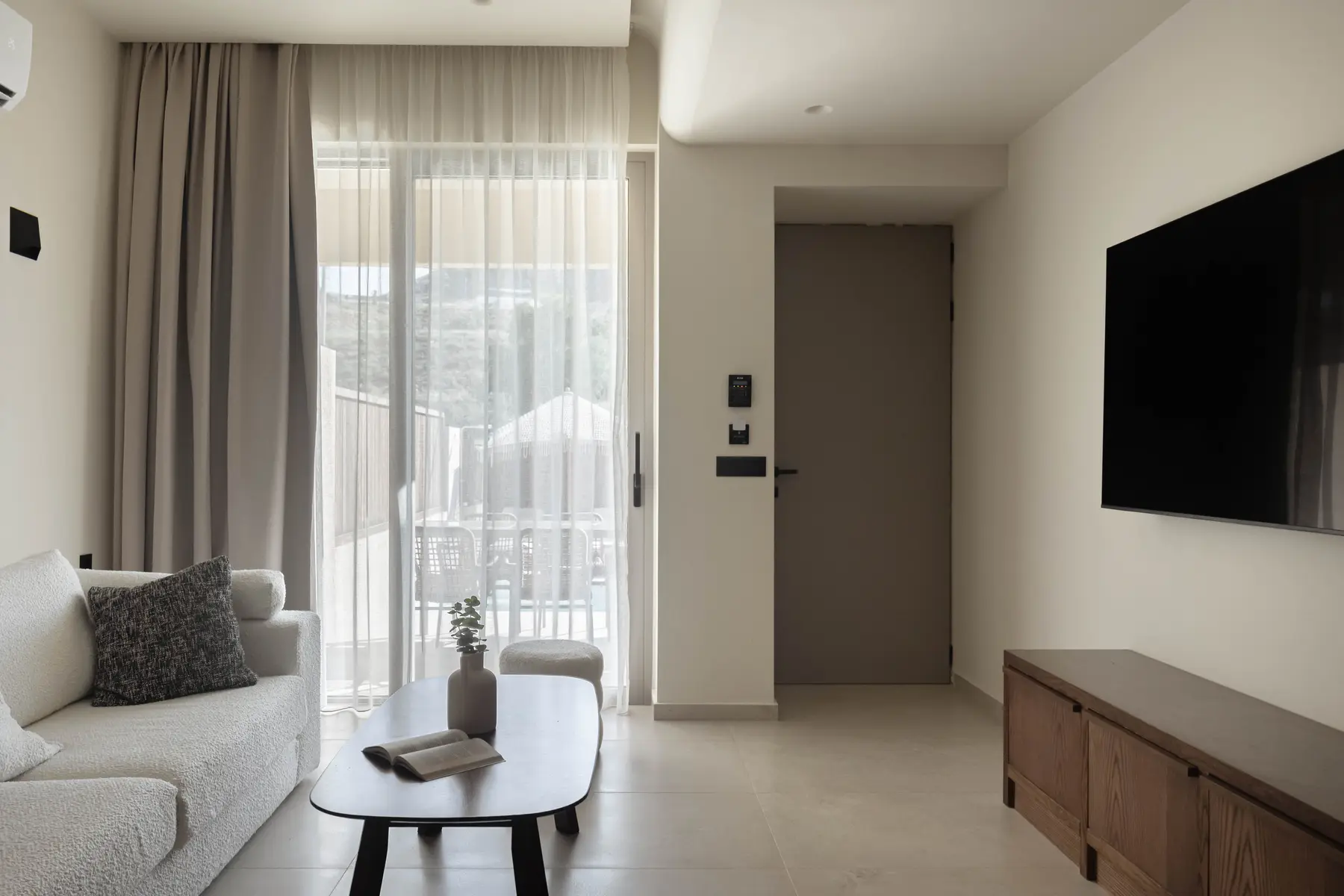 Living room with TV, sofa and balcony beyond
