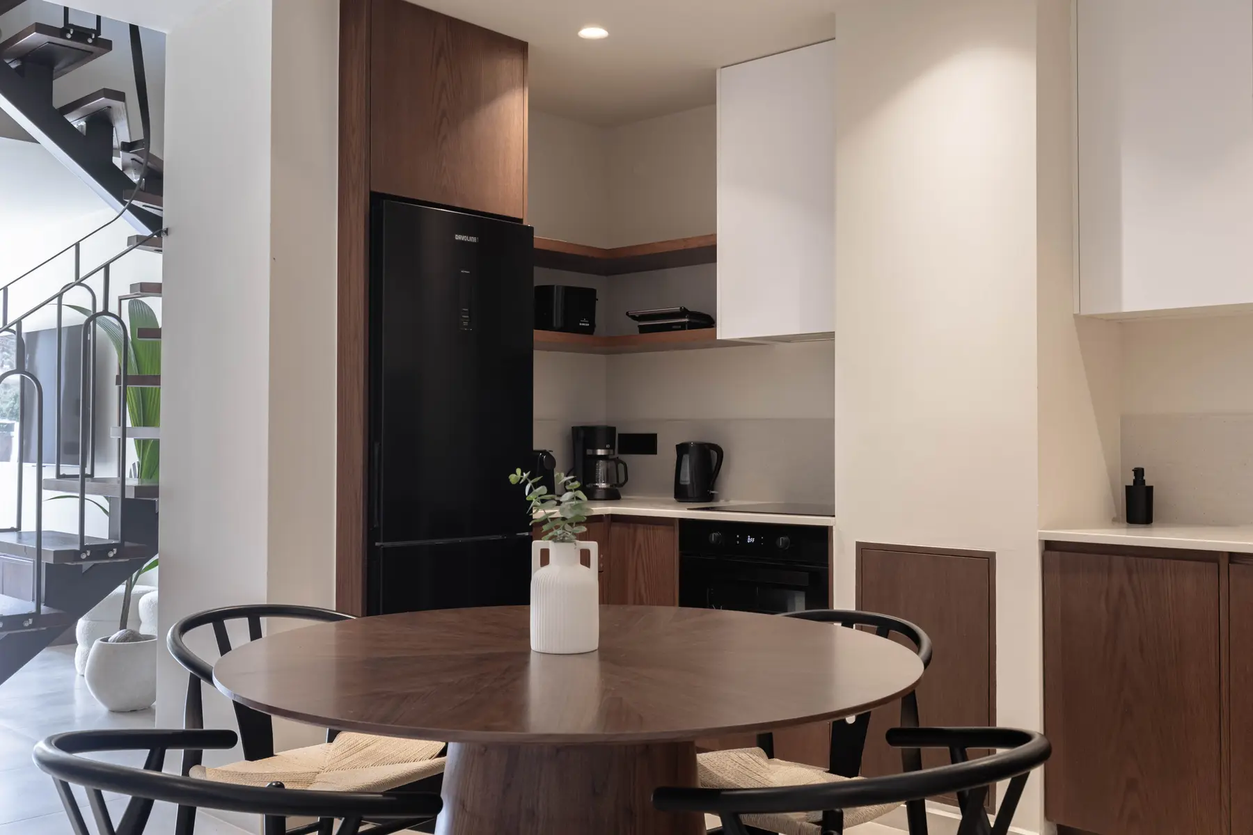 Round dining table and kitchen of the Two-Bedroom Suite under the staircase