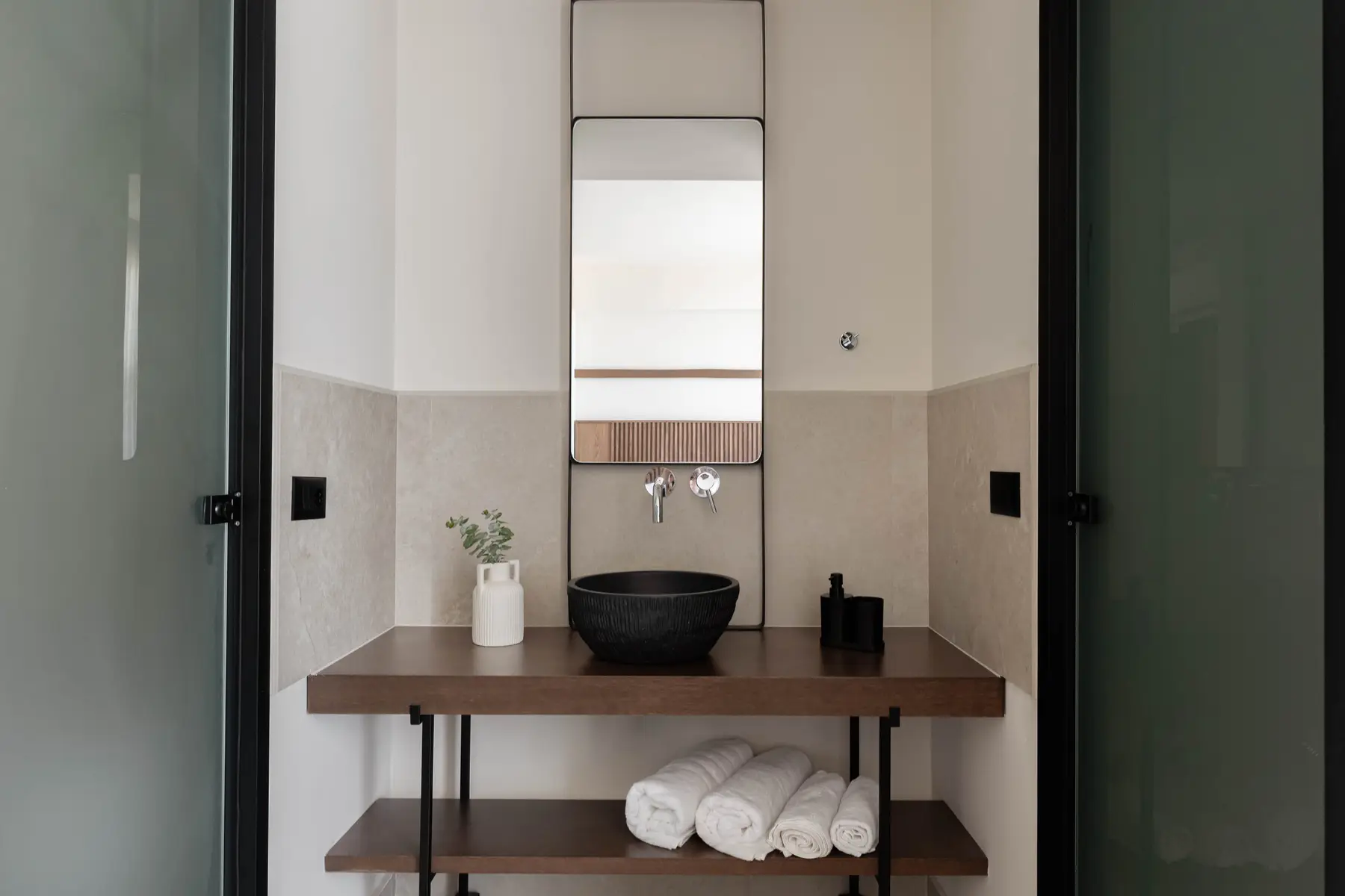 Bathroom vanity with black stone basin and rolled towels